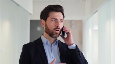 Kendine güvenen ve iyi giyimli iş adamı bir müşterisiyle cep telefonunda konuşarak birden fazla iş yapıyor. Zamanını etkili bir şekilde yönetebilme yeteneği, çok yönlü ve çok yönlü.