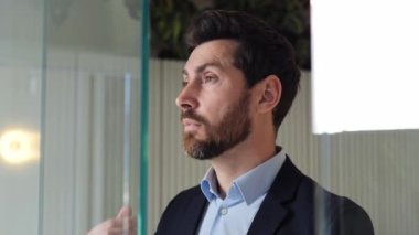 Çok çalışan, kariyerinde açıkça başarılı, cam bir duvarın önünde duran, burnunun köprüsüne masaj yapmak için gözlüğünü çıkaran bitkin bir iş adamı. Ofiste geçirdiği uzun saatler yüzünden baş ağrısı başladı.