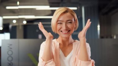 Neşeli sarışın, şaşkın iş kadını serbest çalışan elini yüzüne koyuyor ve ofis yerinde samimi bir şekilde gülümsüyor, olumlu bir sonuç, iyi haber, kazanan coşkuyu kazanıyor, sürpriz, harekete geçme çağrısı