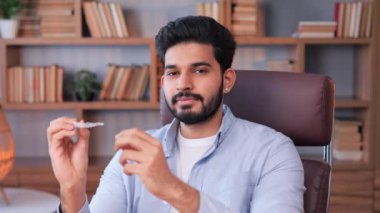 Ortodontik kapaklar, diş dolgunluğu ve geniş interdental boşlukları düzeltmek için tasarlanmıştır. Hintli bir adam ofisteki bir diş plakasını işaret ediyor, diş problemleri, düzensizlik ya da ısırık sorunları gösteriyor.
