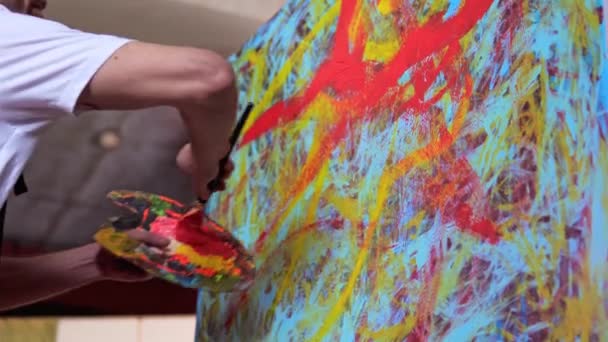 혁신적 예술가는 붓으로 스튜디오의 캔버스에 그림을 그리고 있습니다 다채롭고 감정적 — 비디오