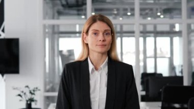 Güzel, şık, gülümseyen iş kadını portresi kameraya bakıp kendinden emin görünüyor. Geniş gülücük, mavi gözler. Siyah kıyafetler giyiyor, modern ofis geçmişi var. Gerçek insanlar dizisi