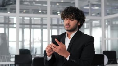 Latin bir adam ofisteki cep telefonundan çok kötü haberler okuyor. İşadamı şok oldu, hayal kırıklığına uğradı, muhtemelen bir sözleşme ihlali ve finansal kayıptan dolayı. Olumsuz olayların iş hayatında duygusal etkisi