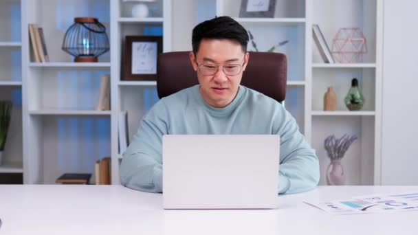 中国のカリスマビジネスマンはオフィスで働いています 彼のラップトップのキーボードを入力し 顧客との通信 人間は集中し 効率的で 強い仕事倫理と細部への注意を持っている — ストック動画