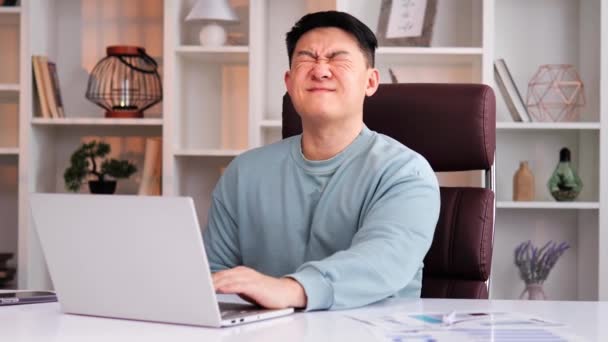 中国のビジネスマンはオフィスで熱心に仕事をしており ラップトップのキーボードを入力して顧客と通信しています 男は胃の痛みと下痢や胃炎に苦しんでいます — ストック動画
