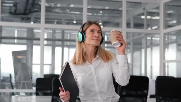 Cheerful Funny Businesswoman Dances Green Wireless Headphones Holding Cup Coffee — Stock Video
