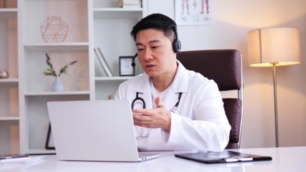 Азиатский Врач Наушниках Проводит Онлайн Конференцию Консультации Пациентом Через Веб — стоковое видео