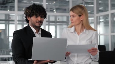 Avrupalı kadın ve Hintli erkekten oluşan kültürler arası ekip, ofis sınırları içinde samimi bir tartışmanın ortasındalar. Kadın bir belgeyi tutarken adam dizüstü bilgisayar tutarken görülüyor.