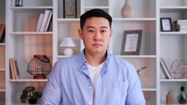 オフィスでは 中国のビジネスマンの深刻な肖像画 焦点を当てた視線でカメラを見て プロの衣装は 彼の分野での自信と専門知識を強調しています リーダーシップと決意 — ストック動画