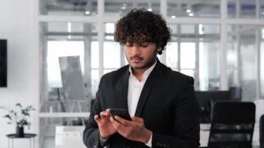 Mutlu Hintli iş adamı cep telefonundan bir telefon numarası giriyor ve ofis ortamında iş ortağıyla konuşuyor. Adam önemli bir iş görüşmesi yapıyor ya da belki bir görüşme ayarlıyordur.