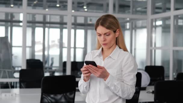 Europejska Kobieta Biurze Trzyma Smartfona Zdenerwowana Otrzymaniem Strasznych Wiadomości Przez — Wideo stockowe