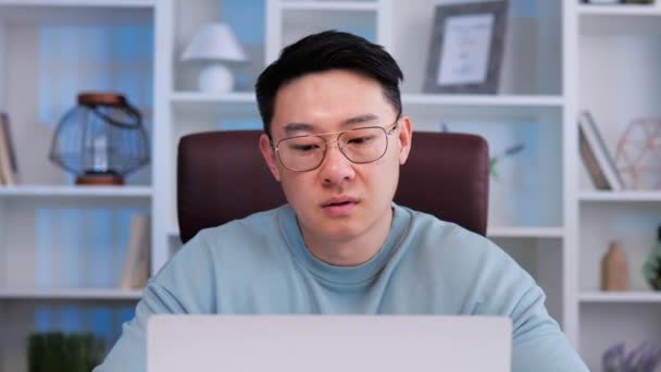 オフィスで燃え尽き 退屈感 悲しみ 疲れを経験するメガネを持つアジア系男性のオフィスワーカー ラップトップで働く努力にもかかわらず 中国の男は彼の仕事への熱意を示していません — ストック動画