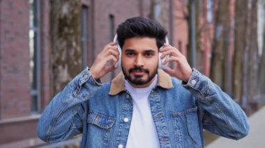 Akıllı telefonda müzik uygulaması kullanarak kot ceket giyen şık bir adam. Adam kulaklıklarını çıkarıyor, kameraya gülümsüyor gençliğin modaya uygun ve kentsel yaşam tarzını temsil ediyor. Teknoloji ve moda