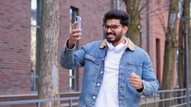Heyecanlı Hintli iş adamı ödül kazanmakla ya da büyük bir zafer kazanmakla ilgili harika haberler alıyor. Bu da onu hayrete düşürüyor ve şaşırtıyor. Cep telefonundan gelen haberlere şaşırtıyor.