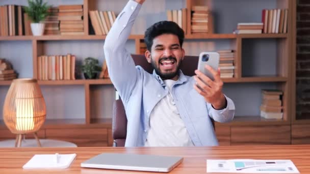 Udany Hinduski Biznesmen Biurze Patrząc Telefon Komórkowy Wyrazem Triumfu Lub — Wideo stockowe
