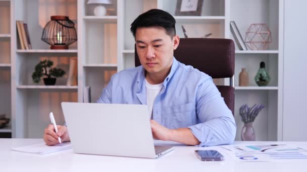 아시아 회계사는 사무실에 앉아서 펜쓰기 결과를 있습니다 노트북에 사용하고 보고서를 — 비디오