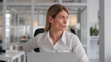 Ofiste dizüstü bilgisayarda çalışan kadın sırt ağrısı çekiyor. Uzun süreli oturma ve kötü duruş ofis çalışanlarında sık görülen sırt ağrısıdır. Ara vermeli, esnemeli ve duruşunu korumalısın.