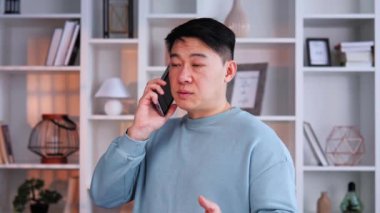 Genç Asyalı iş adamı bilişim sektöründe çalışıyor. Ofisinde günlük kıyafetlerini giymiş ve cep telefonuyla konuşuyor. Ciddi bir adam işiyle ilgili önemli bir konuşma yapıyor.