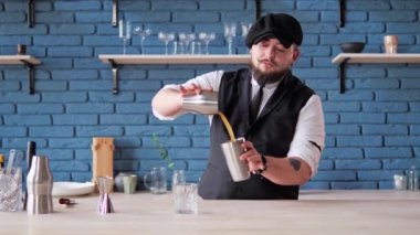 Barmen profesyonel hazırlıkları bir bar veya restoranda alkollü içecekler servis eder. Adam kokteyli sallıyor, barmen malzemeleri karıştırıcının içine koyuyor ve güçlü bir şekilde sallıyor köpüklü bir doku oluşturuyor.