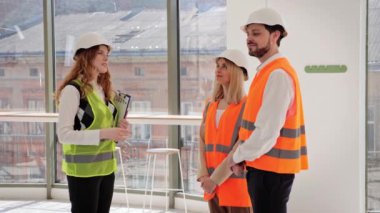 Profesyonel kadın emlakçı, içinde belgeler olan bir dosya tutuyor ve bir kafe projesi de mülkü yatırımcılara gösteriyor. Genç bir çift işleri için yer satın almayı düşünüyor.