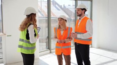 Koruyucu giysi ve kask yatırımcıları bir emlakçı veya komisyoncuyla bir mülkün satın alınması veya satışı hakkında görüşmek üzere bir araya geliyorlar. Genç yatırımcılar iş için bir yer düşünüyor.