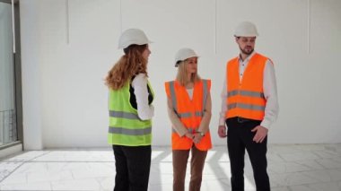 Koruyucu giysi ve kask giymiş bir grup yatırımcı, emlak alım satımı veya satımı konusunda görüşmek üzere bir emlakçı veya komisyoncuyla görüşüyor. Yatırımcılar iş girişimiyle ilgili bir alanı değerlendiriyorlar.