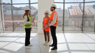 Koruyucu teçhizat ve kask takan yatırımcılar, bir emlakçı veya komisyoncuyla bir mülkün satın alınıp satılmasını tartışmak üzere bir araya geldiler. Yeni iş, kafe veya restoran bürosu