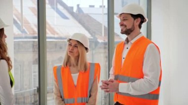 Koruyucu giysiler içindeki çekici genç yatırımcılar bir emlakçı veya komisyoncuyla bir emlak satın alma veya satışı hakkında görüşmek üzere bir araya geliyorlar. Gülümseyen insanlar iş için yer ararlar.