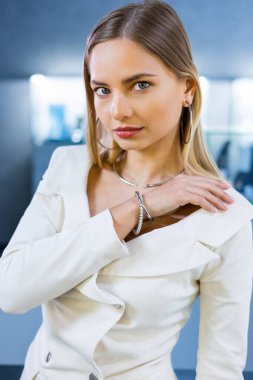 Vücudunda altın elmas aksesuarlar olan çekici bir kızın portresi. Güzel bir cilt yüzlü bayan, bir kuyumcudaki kameraya bakıyor. Gelin bir bilezik, kolye ve küpe takıyor.