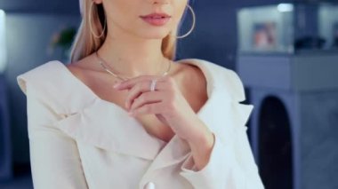 Göz kamaştırıcı güzellikte bir model bir kuyumcuda aynada durur ve kızın üzerinde parıldayan altın bir elmas kolye dener. Kız lüks bir butikte altın mücevher ve elmaslarla süslenir.