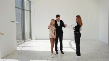 Sevgili aile çiftimiz boş apartman dairesinde profesyonel emlakçıyla daire alışverişini tartışıyor, kağıt sözleşmesi imzalıyor, kendi konaklama yerinin anahtarlarını alıyor, başarılı bir anlaşma, anahtar...