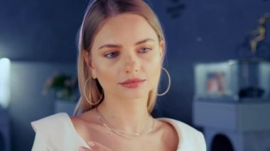 Evlatlık edinilebilecek güzel bir model bir kuyumcuda aynada durur ve kızın üzerinde parıldayan altın bir elmas kolye dener. Kız lüks bir butikte altın mücevher ve elmaslarla süslenir.