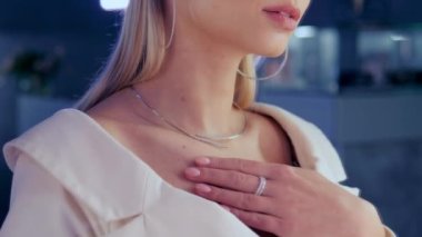 Sihirli güzel model bir kuyumcuda aynada durur ve kızın üzerinde parıldayan altın elmas bir kolye dener. Kız lüks bir butikte altın mücevher ve elmaslarla süslenir.