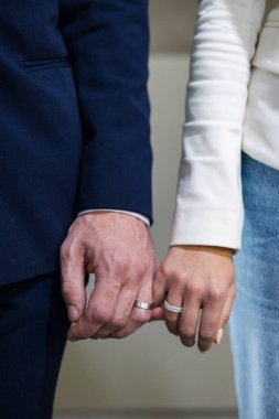 Nişanlı çift birbirine dokunuyor mücevher mağazasında parıldayan elmas yüzüklerini sergiliyorlar. Yüzüklü kadın ve erkek, altın hazinelerle dolu bir mağazada el ele tutuşuyorlar.