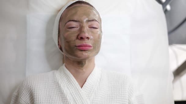 Красивая Женщина Лежит Клинике Красоты Белом Халате Зеленой Маской Лице — стоковое видео