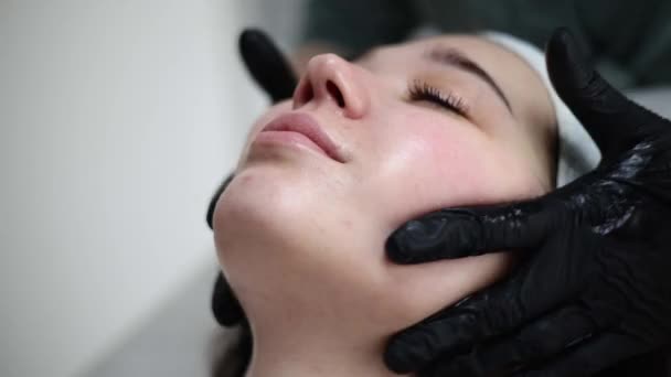 洗浄し 栄養肌を保湿 クリームマスクの美容師は施術後にマッサージを受ける 顔の剥離を受ける美しい女性 美容室のトリートメントスキンケア美容室 — ストック動画