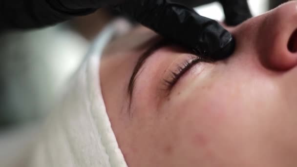 Der Kosmetologe Trägt Eine Maske Unter Der Augencreme Auf Die — Stockvideo