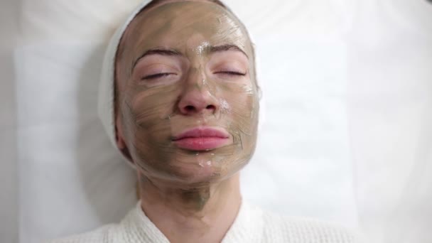女性は美容クリニックに滞在し 肌を若返らせることを目的とした緑色の顔マスクをスポーツします アクティブクレンジングリフティング治療効果的に戦うにきび拡大毛穴の外観を減少させます — ストック動画