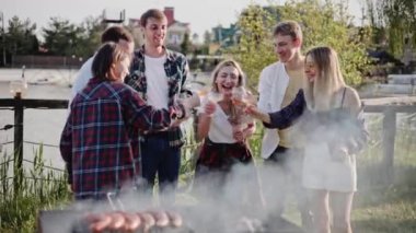 Mutlu arkadaşlar göl kenarında şarkı söyleyip dans ediyorlar.