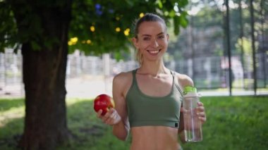 Spor giyimli kız kırmızı elma ve suyu şişede tutuyor. Sağlıklı bir yaşam tarzı.