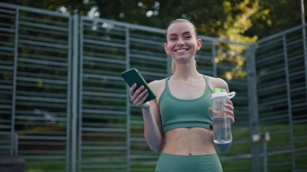 Ung Atletisk Kvinna Sportkläder Med Mobiltelefon Och Vattenflaska — Stockvideo