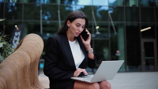 Jovem Menina Negócios Usar Laptop Sentado Banco Fora Falando Telefone — Vídeo de Stock