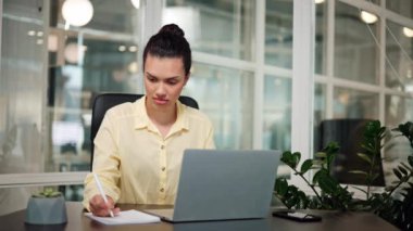 Akıllı Afro-Amerikalı kadın dizüstü bilgisayarda çalışıyor ve not alıyor.