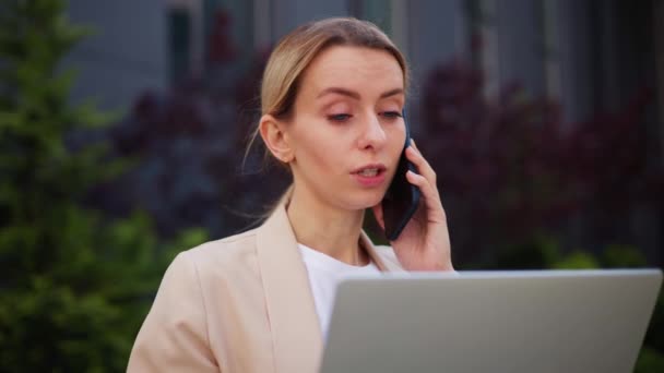 Jonge Vrouw Met Laptop Tijdens Het Communiceren Met Mobiele Telefoon — Stockvideo