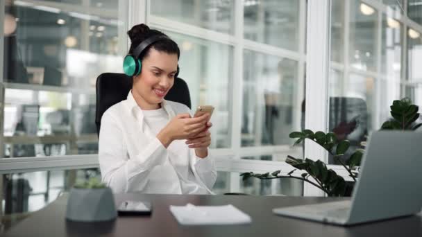 陽気なラテンアメリカのオフィスワーカーが緑色のヘッドフォンで音楽を聴く — ストック動画