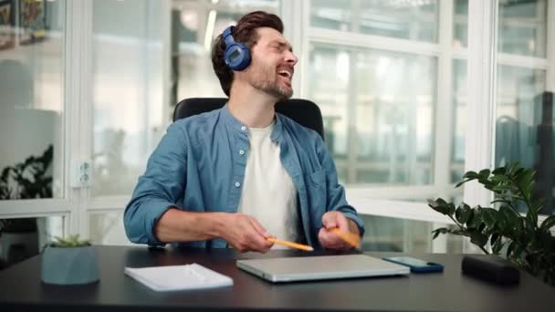 楽しい仕事休憩を楽しんでいるブルーヘッドフォンの陽気で面白いビジネスマン — ストック動画