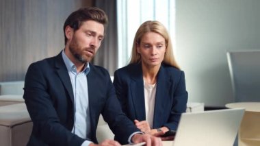 Beyaz adam ve kadın, parlak ofis alanındaki iş görüşmeleri sırasında kablosuz bilgisayar kullanıyorlar. Şık siyah takım elbiseli, kendine güvenen meslektaşları yuvarlak masada oturup şirket konferansının keyfini çıkarıyorlar..