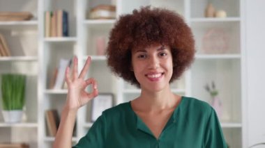 Güzel afro-amerikan kadını ofiste olumlu duygularını ifade ederken parmaklarıyla jest yapıyor. Çekici genç bayan bir şeyi kabul etmek için el işareti yapıyor..