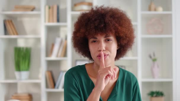微笑着的非洲裔美国女人在把手指放在嘴上的时候表现出沉默的姿态 优雅快乐的女性要求在设计办公室的内部背景下保持安静 — 图库视频影像