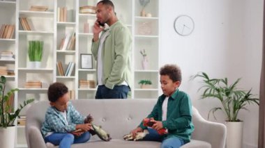 İki çocuk rahat koltukta oyuncaklarla oynarken genç bir baba eve girip akıllı telefondan konuşuyor. Sıradan giyinmiş Afro-Amerikan ailesi evde vakit geçiriyor..
